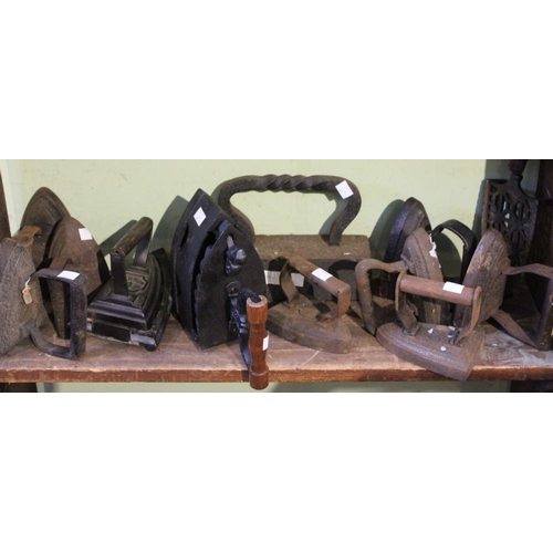 139 - A shelf of vintage cast iron flat and smoothing irons