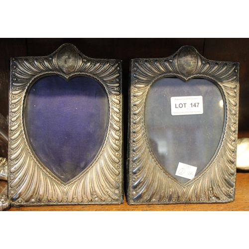 147 - A pair of silver mounted photograph frames, embossed decoration, the image revealed in a heart shape... 