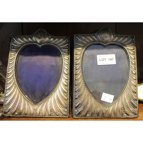 147 - A pair of silver mounted photograph frames, embossed decoration, the image revealed in a heart shape... 