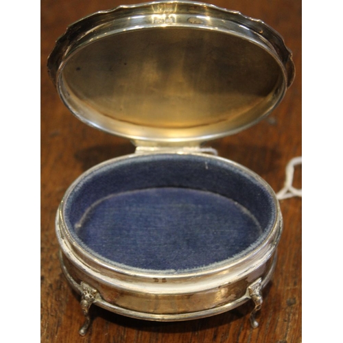 158 - A silver trinket or ring box, oval shape, hinged lid reveals blue fabric interior, raised on cabriol... 