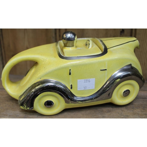 134 - An Art Deco design sports car ceramic teapot, yellow glaze with silvered detail, number plate 