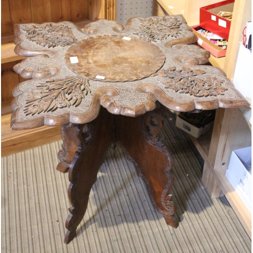 173 - A heavily carved Anglo-Indian occasional table on four folding legs