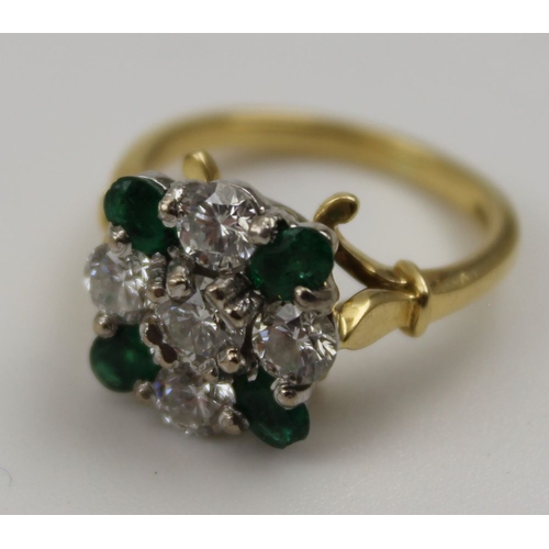 10 - A diamond and emerald ring, set five brilliant cut diamonds in a cross form, having four oval cut em... 