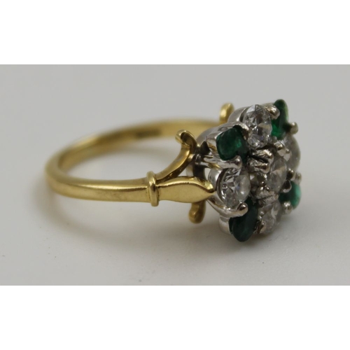 10 - A diamond and emerald ring, set five brilliant cut diamonds in a cross form, having four oval cut em... 