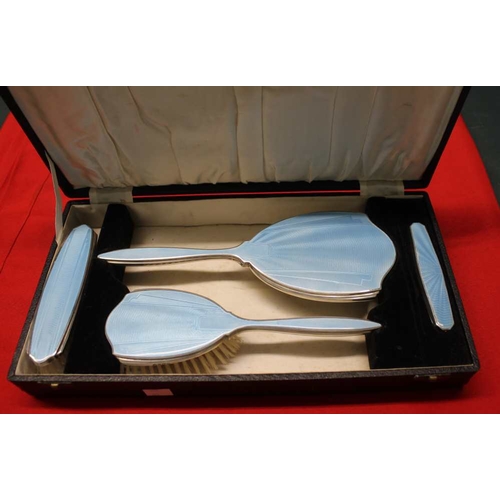 23 - A cased pale blue enamel and silver four piece dressing table set. Two brushes, mirror and nail buff... 