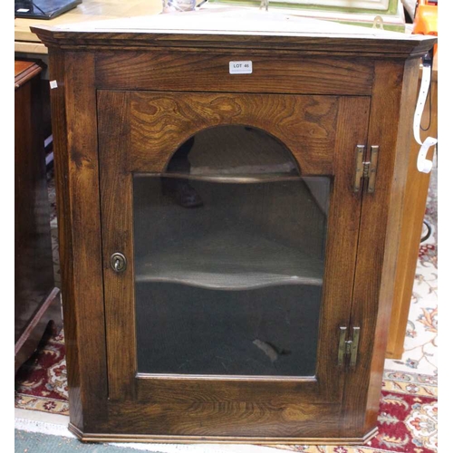 46 - A Georgian design elm hanging corner cupboard, the arch glazed panel in the door reveals two interna... 