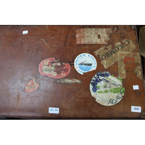 302 - A vintage leather suitcase with various travel stickers