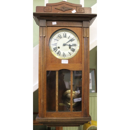 64 - A 20th century wooden carved wall clock with pendulum and key