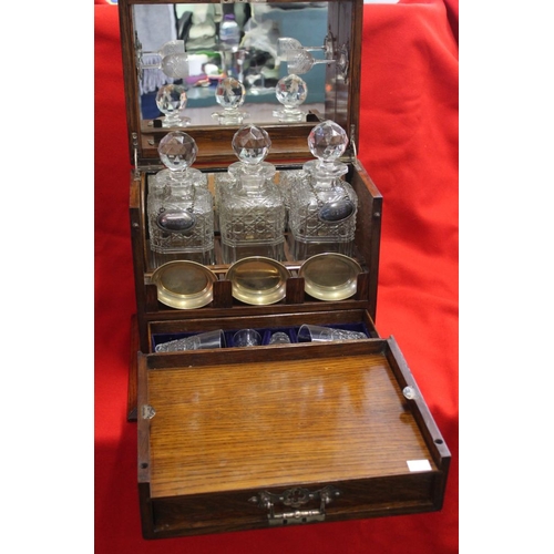 355 - An Edwardian oak Tantalus cabinet, contains three cut glass spirit decanters, various glasses, cabin... 