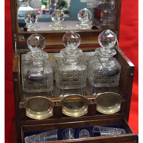 355 - An Edwardian oak Tantalus cabinet, contains three cut glass spirit decanters, various glasses, cabin... 