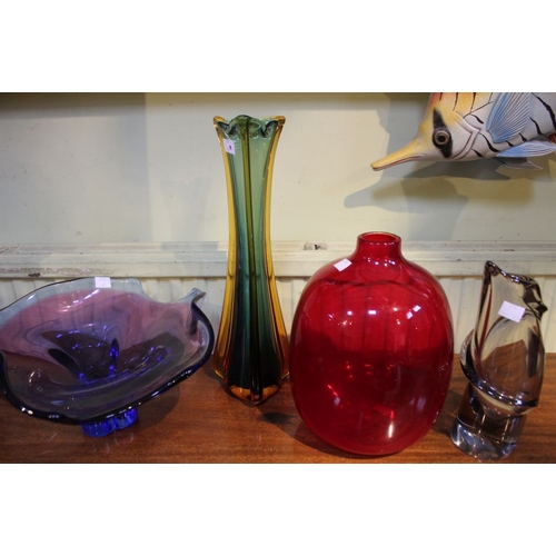 142 - Four pieces of glass, a tall amber & green vase, a red squat vase, a blue example & a smoked glass v... 