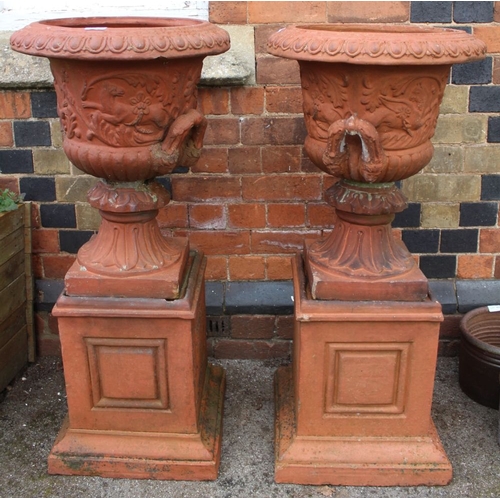 463 - A pair of terracotta effect garden urns of Campagna form, raised on square plinth bases, overall 103... 