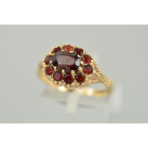 136 - A 9CT GOLD GARNET CLUSTER RING, the central oval garnet within a garnet surround, with leaf detail t... 