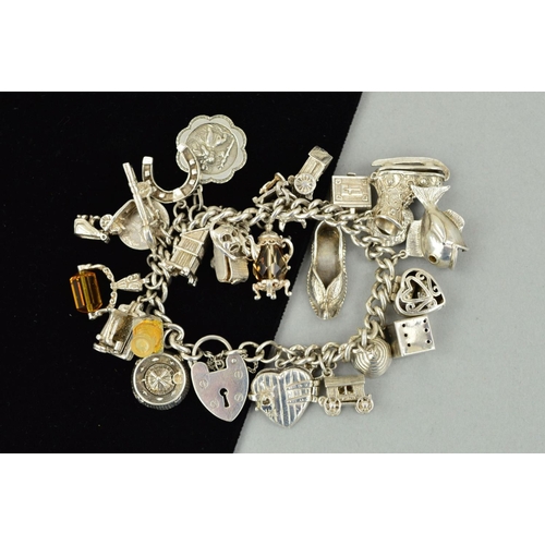 204 - A SILVER CHARM BRACELET, the curb link charm bracelet suspending 26 charms to include a hinged camer... 