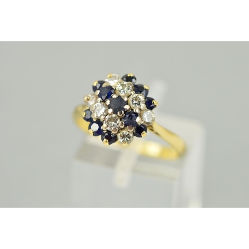 205 - A SAPPHIRE AND DIAMOND CLUSTER RING, designed as three graduated rows of circular sapphires interspa... 