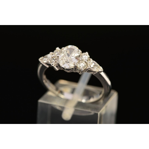 13 - A MODERN PLATINUM DIAMOND DRESS RING, centring on an oval modern brilliant cut diamond, accompanied ... 