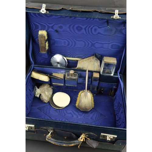 133 - A GEORGE V BLUE LEATHER SUITCASE, with canvas outer cover, the case interior with water marked blue ... 