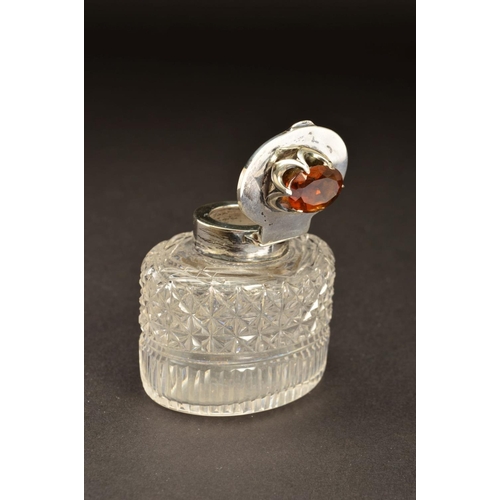 194 - AN EDWARDIAN SILVER MOUNTED OVAL GLASS INKWELL, the hinged cover set with a Cairngorm (brown quartz)... 