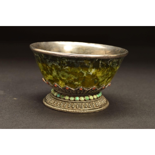 217 - A MIDDLE EASTERN WHITE METAL MOUNTED GREEN STONE BOWL, possibly Connemara marble, the white metal fi... 