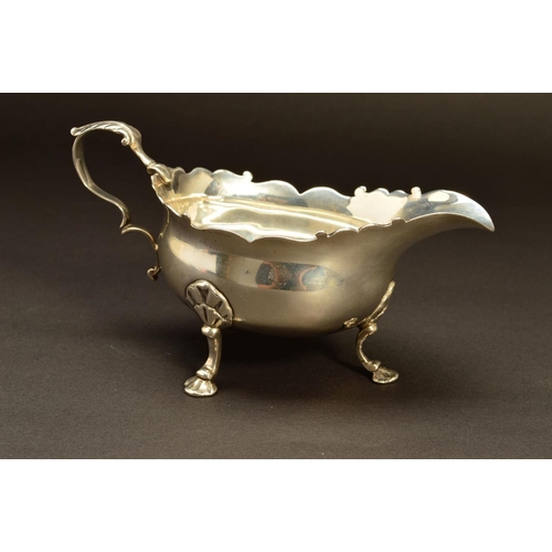 230 - A GEORGE II SILVER SAUCEBOAT, wavy rim, 'S' scroll handle, on three cabriole legs, shell knees and f... 