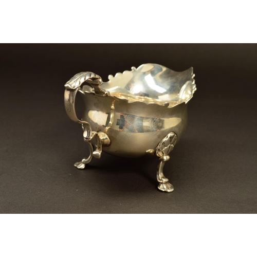 230 - A GEORGE II SILVER SAUCEBOAT, wavy rim, 'S' scroll handle, on three cabriole legs, shell knees and f... 