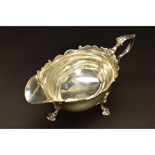 230 - A GEORGE II SILVER SAUCEBOAT, wavy rim, 'S' scroll handle, on three cabriole legs, shell knees and f... 