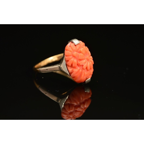 24 - AN EARLY 20TH CENTURY CARVED CORAL RING, an oval floral panel measuring approximately 15mm x 10mm, r... 