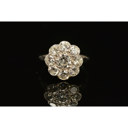 51 - A DIAMOND CLUSTER RING, the central brilliant cut diamond within a surround of eight brilliant cut d... 