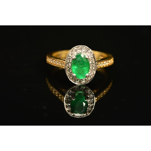 54 - A MODERN 18CT GOLD EMERALD AND DIAMOND HALO CLUSTER STYLE RING, with diamond set shoulders, emerald ... 