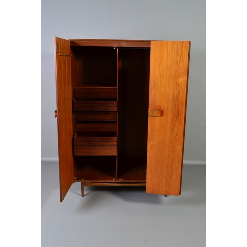 588 - IB KOFOD LARSEN, FOR GPLAN DANISH RANGE, a teak 1960's triple door wardrobe, with double bifold and ... 