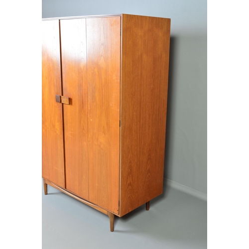 588 - IB KOFOD LARSEN, FOR GPLAN DANISH RANGE, a teak 1960's triple door wardrobe, with double bifold and ... 