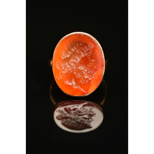 60 - A CARNELIAN INTAGLIO RING, the oval carnelian carved to depict a bearded man, within a collet mount ... 