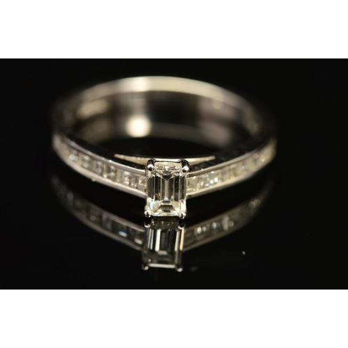 68 - A MODERN EMERALD CUT DIAMOND RING, with square cut diamonds channel set to the shoulders, centre eme... 