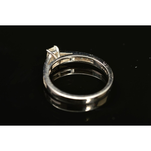 68 - A MODERN EMERALD CUT DIAMOND RING, with square cut diamonds channel set to the shoulders, centre eme... 