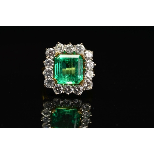 82 - AN IMPRESSIVE 18CT GOLD EMERALD AND DIAMOND CLUSTER RING, centring on an emerald cut emerald measuri... 