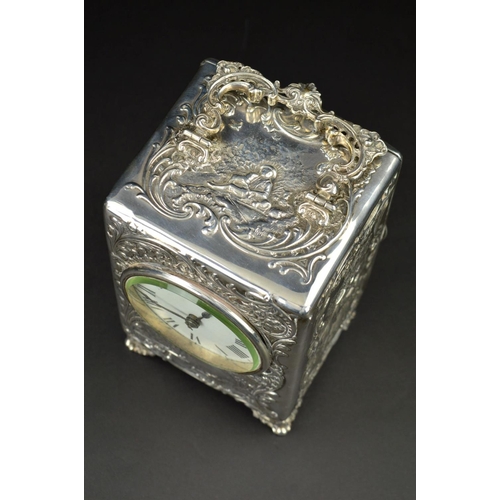 87 - AN EDWARDIAN SILVER CASED BOUDOIR OR CARRIAGE TIMEPIECE, the top with hinged carrying handle cast an... 