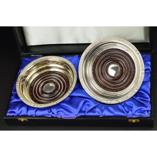 91 - A CASED PAIR OF LATE 20TH CENTURY IRISH SILVER BOTTLE COASTERS, Celtic design borders of scrolls and... 