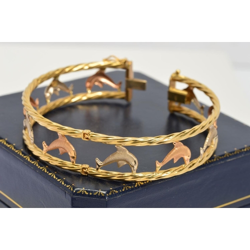 136 - A MODERN THREE COLOUR GOLD DOLPHIN BANGLE, a hinged oval bangle of open work design measuring approx... 