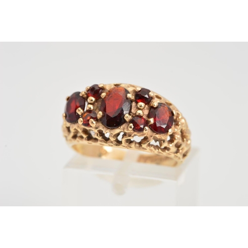 61 - A 9CT GOLD GARNET RING, designed as oval and circular garnets within an open textured surround, 9ct ... 