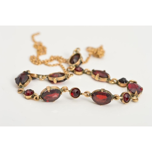 99 - A GARNET NECKLACE, designed as seven oval claw set garnets interspaced by circular garnets to the fi... 