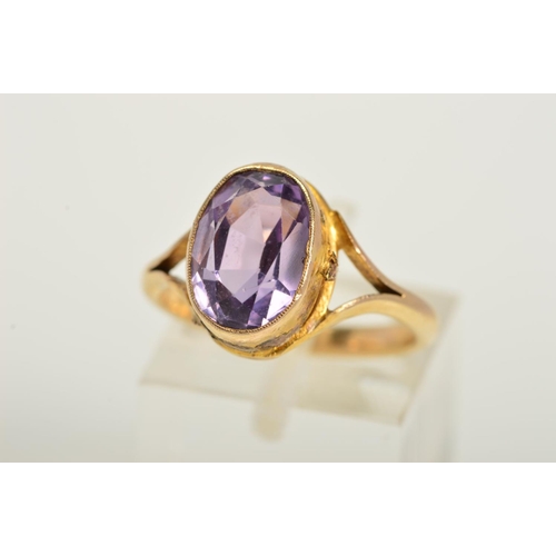 125 - AN AMETHYST RING, designed as a central oval amethyst in a collet setting to the bifurcated shoulder... 