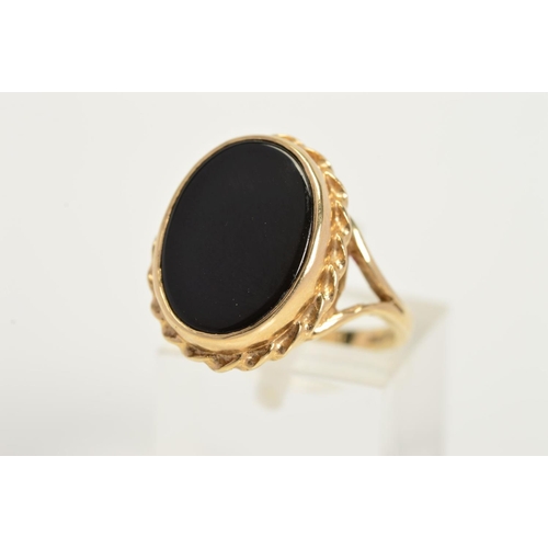 149 - A 9CT GOLD ONYX RING, designed as an oval onyx panel in a collet setting within a rope twist surroun... 