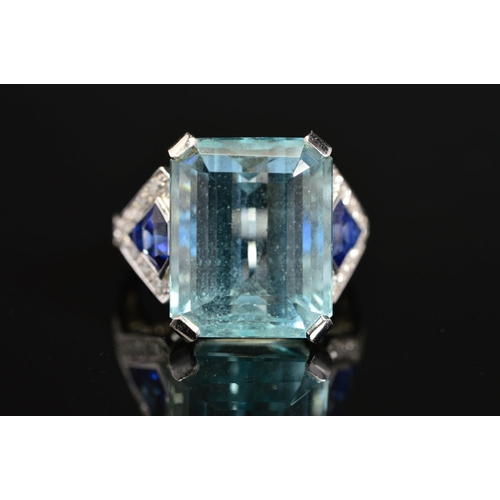 10 - A MODERN AQUAMARINE, SAPPHIRE AND DIAMOND DRESS RING, centring on a principal trap cut aquamarine me... 