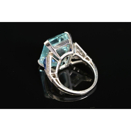 10 - A MODERN AQUAMARINE, SAPPHIRE AND DIAMOND DRESS RING, centring on a principal trap cut aquamarine me... 