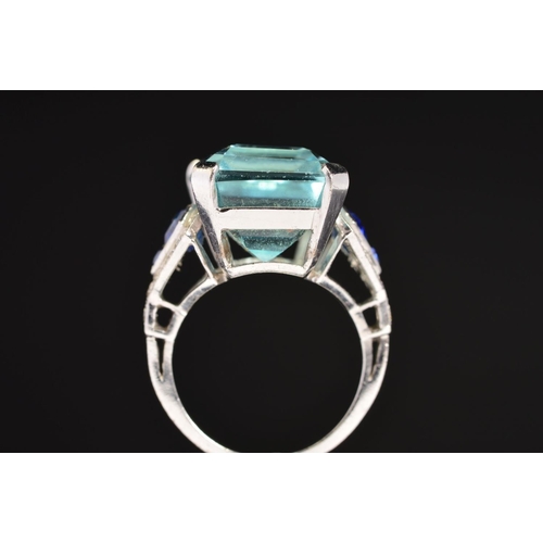 10 - A MODERN AQUAMARINE, SAPPHIRE AND DIAMOND DRESS RING, centring on a principal trap cut aquamarine me... 