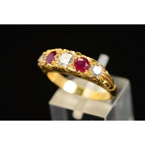 25 - A LATE 20TH CENTURY 18CT RUBY AND DIAMOND CARVED HALF HOOP FIVE STONE RING, scroll carved shoulders ... 