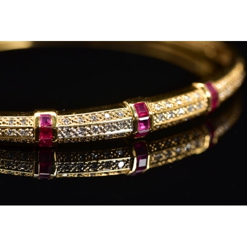 45 - A MODERN 18CT GOLD, RUBY AND DIAMOND HALF HOOP BANGLE, an oval hinged bangle fitted to tongue and bo... 