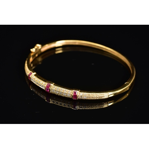 45 - A MODERN 18CT GOLD, RUBY AND DIAMOND HALF HOOP BANGLE, an oval hinged bangle fitted to tongue and bo... 