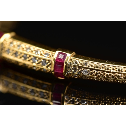 45 - A MODERN 18CT GOLD, RUBY AND DIAMOND HALF HOOP BANGLE, an oval hinged bangle fitted to tongue and bo... 