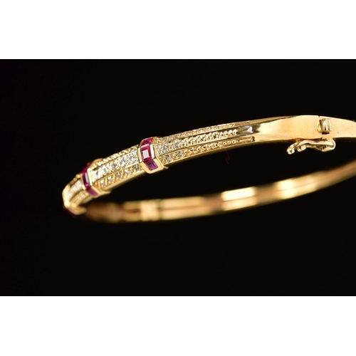 45 - A MODERN 18CT GOLD, RUBY AND DIAMOND HALF HOOP BANGLE, an oval hinged bangle fitted to tongue and bo... 